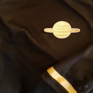 close up of a uniform on the Galactic Trek star ship. its brown and the symbol is Saturn. 