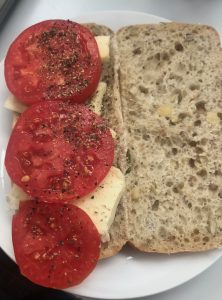 a tomato, cheese roll with pepper. It is open with ingredients to the left