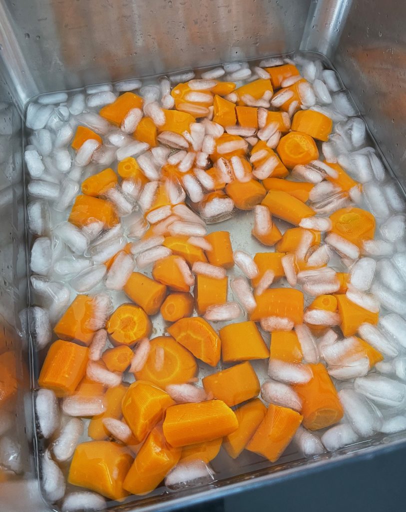 a kitchen sink, cooked carrots and lots of ice and water