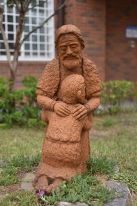 A touching statue representing the <strong>Parable of the Lost Son</strong>, showing a father embracing his returning son with compassion, forgiveness, and grace. The image reflects themes of restoration, repentance, unconditional love, and Christian faith through suffering and hardship.