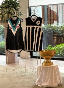 How to use ChatGPT to write a eulogy - Port Adelaide Power and Port Adelaide Magpies guernseys displayed with football memorabilia at Alec Duthie's funeral.